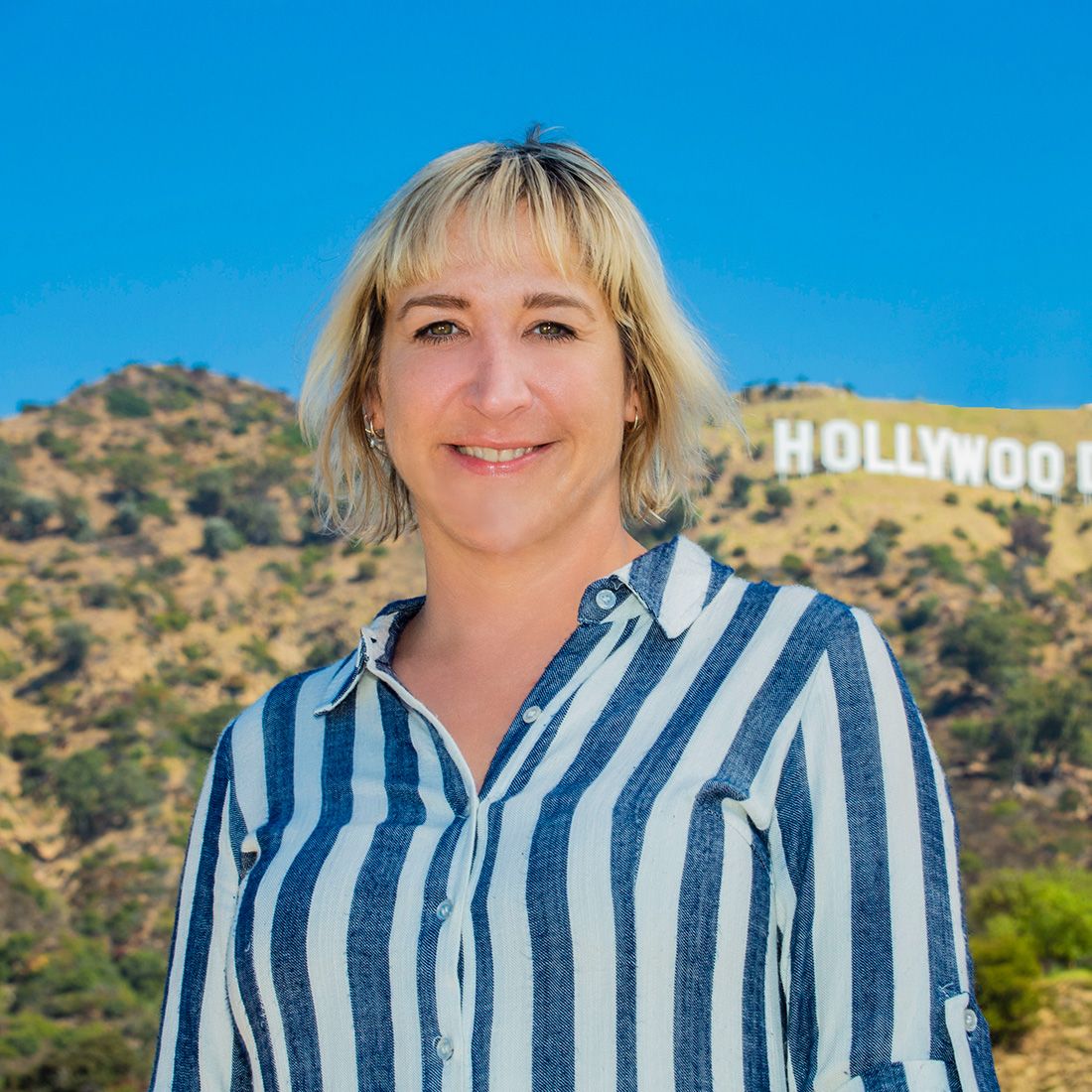 Lauren Smith Wells has short, straight blonde hair and brown eyes, and is wearing a black zip front top